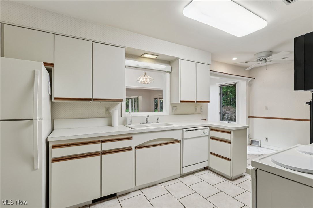 33300 South Woodland Road Cleveland, OH 44124 - Photo 25 of 50 Kitchen with white cabinets, white appliances, light countertops, light tile patterned flooring, and a peninsula
