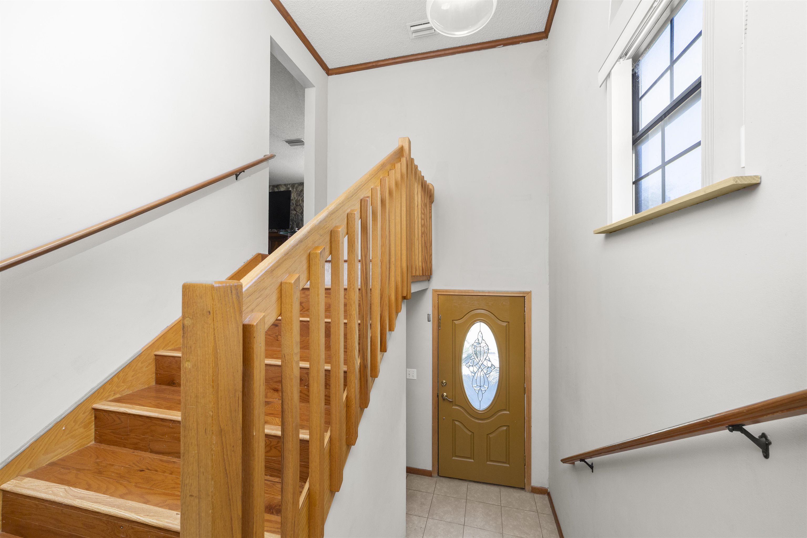 545 Ray Edwards Road St. Augustine, FL 32086 - Photo 23 of 78 Staircase with crown molding, tile patterned flooring, and a high ceiling