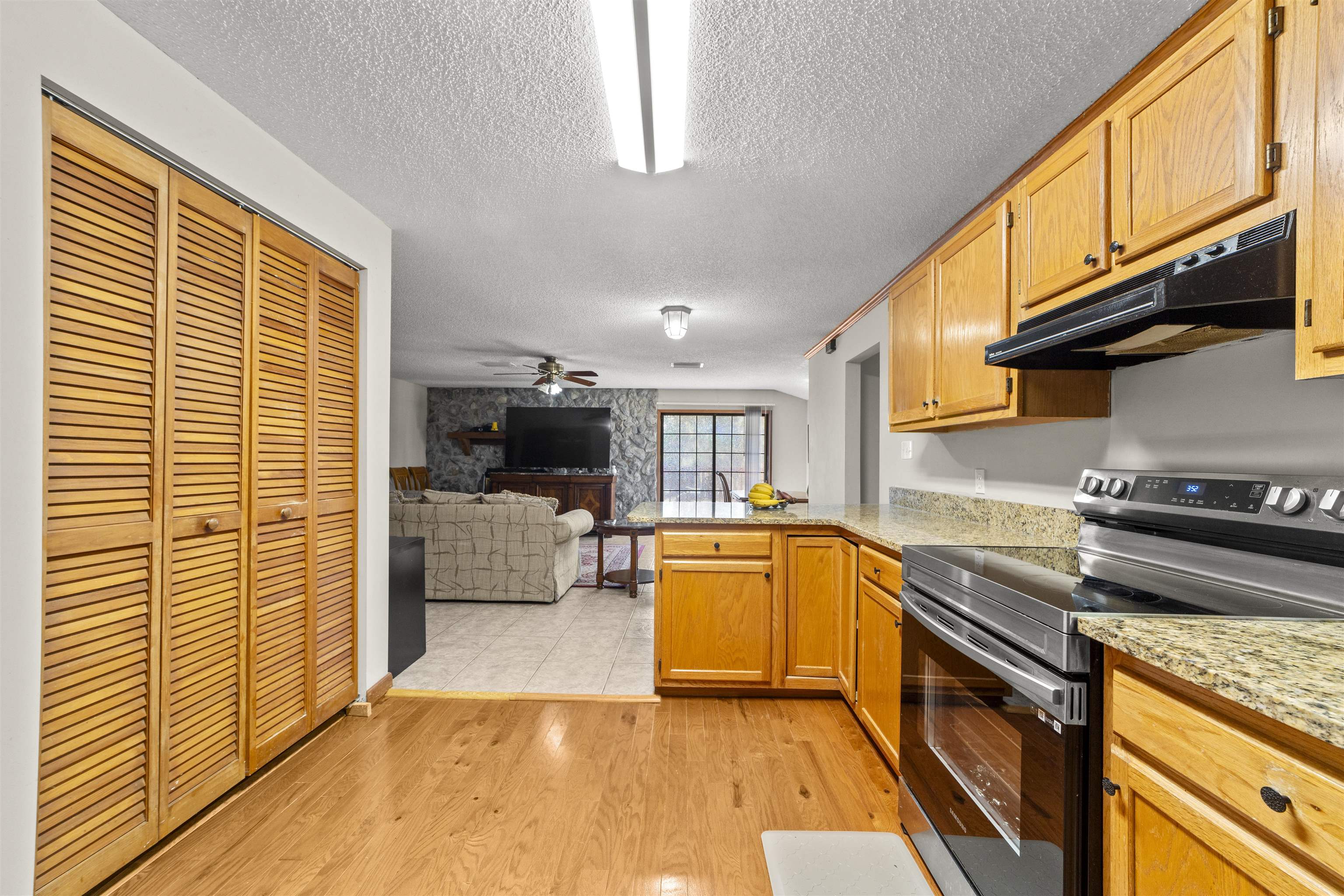 545 Ray Edwards Road St. Augustine, FL 32086 - Photo 78 of 78 Kitchen featuring stainless steel range with electric cooktop, a peninsula, open floor plan, under cabinet range hood, and light stone countertops