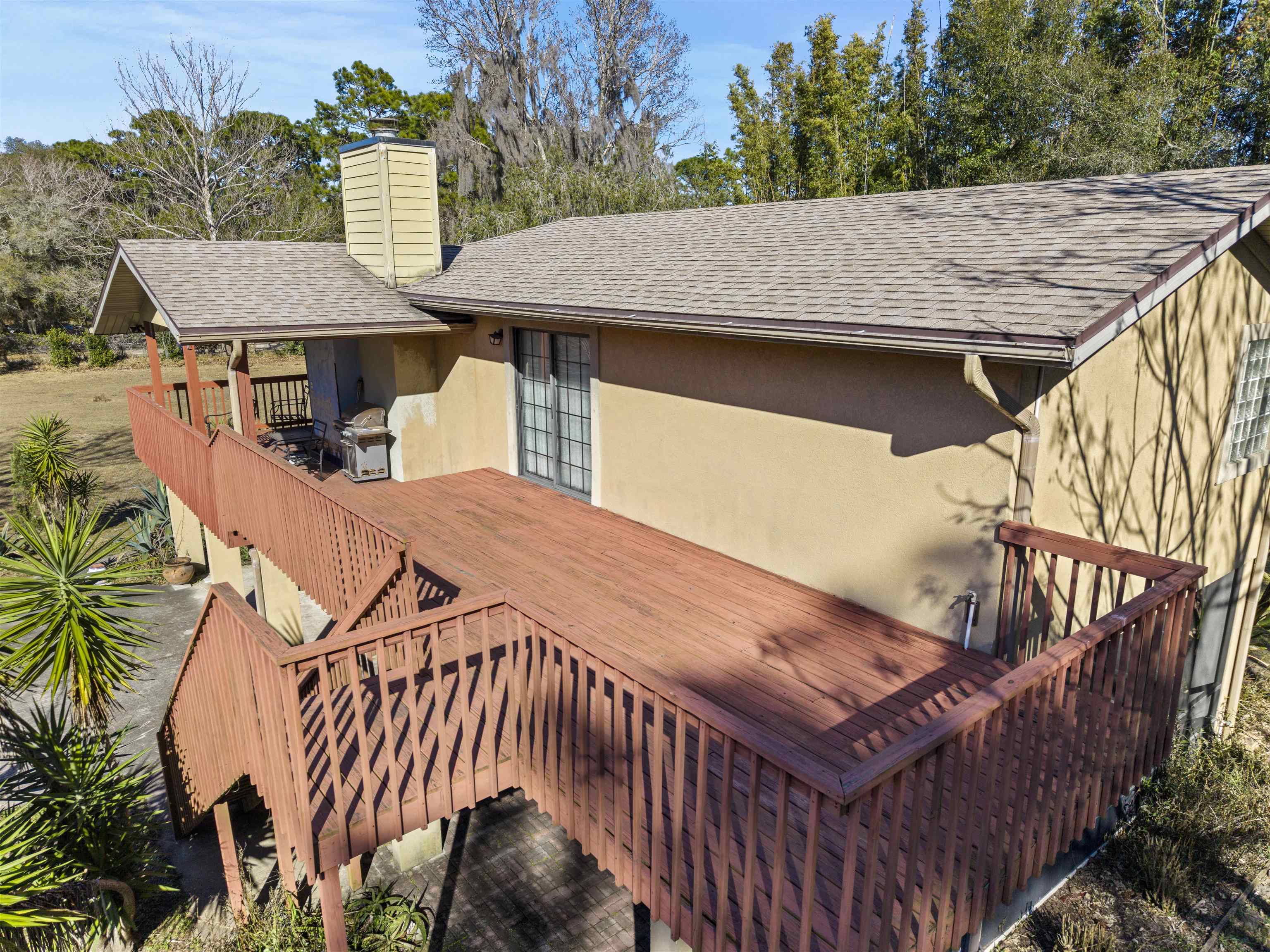 545 Ray Edwards Road St. Augustine, FL 32086 - Photo 3 of 78 Back of house featuring stucco siding, a shingled roof, a chimney, a wooden deck, and stairway