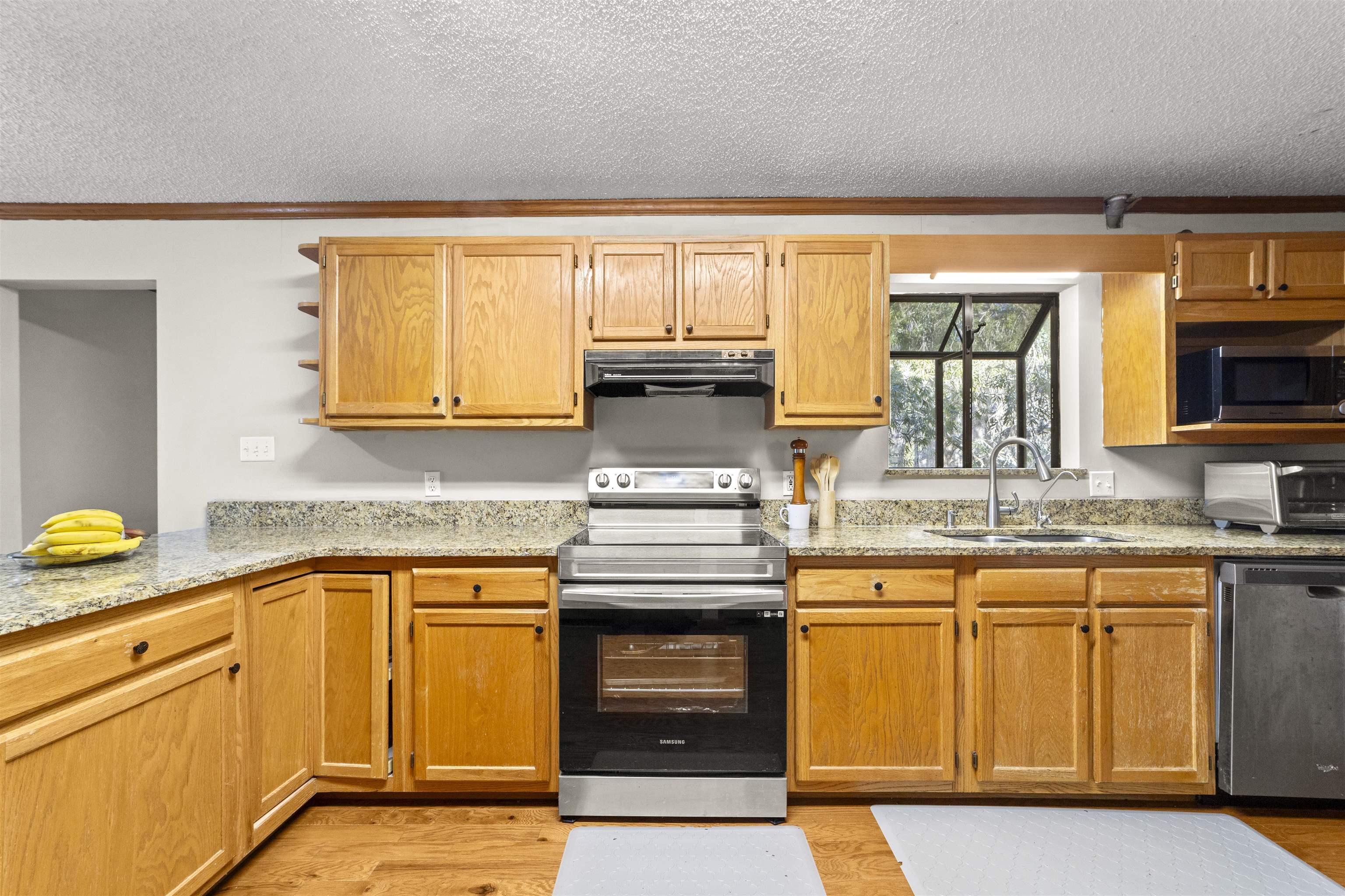 545 Ray Edwards Road St. Augustine, FL 32086 - Photo 30 of 78 Kitchen featuring appliances with stainless steel finishes, crown molding, open shelves, a textured ceiling, and light stone counters