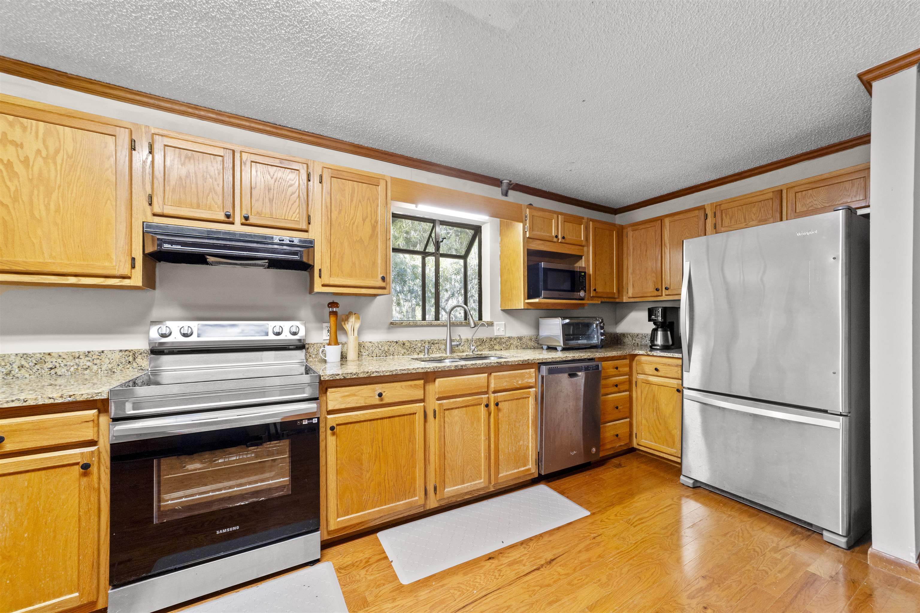 545 Ray Edwards Road St. Augustine, FL 32086 - Photo 31 of 78 Kitchen with stainless steel appliances, crown molding, under cabinet range hood, a textured ceiling, and light stone countertops