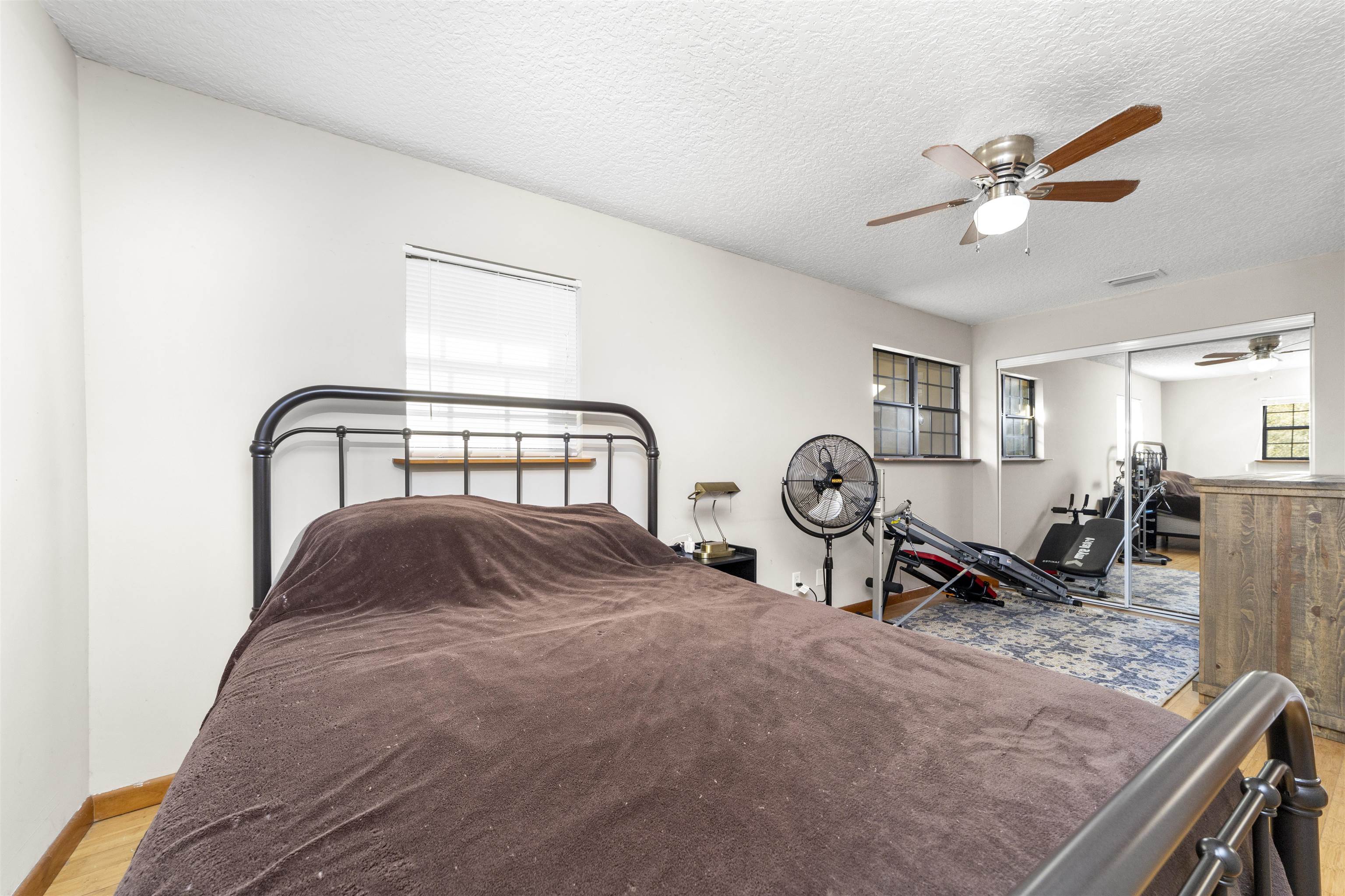 545 Ray Edwards Road St. Augustine, FL 32086 - Photo 36 of 78 Bedroom featuring a ceiling fan, a textured ceiling, a closet, and light wood finished floors