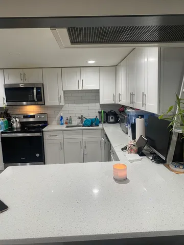 a kitchen with stainless steel appliances a stove a sink a microwave a refrigerator and cabinets