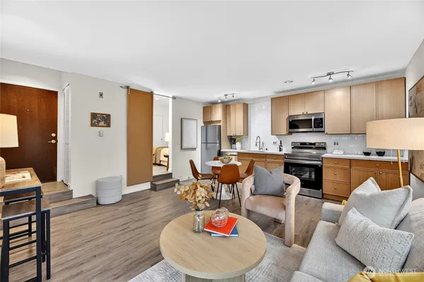 a living room with furniture kitchen view and a wooden floor