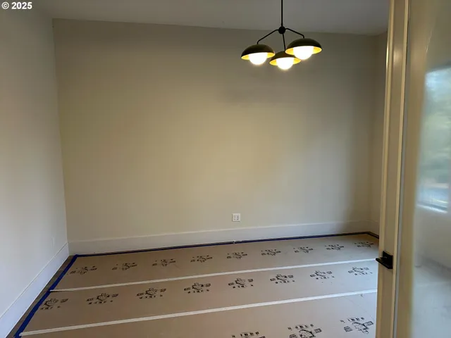 a view of an empty room and chandelier fan