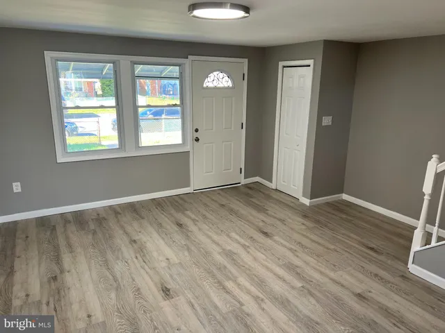a view of an empty room with a window and wooden floor