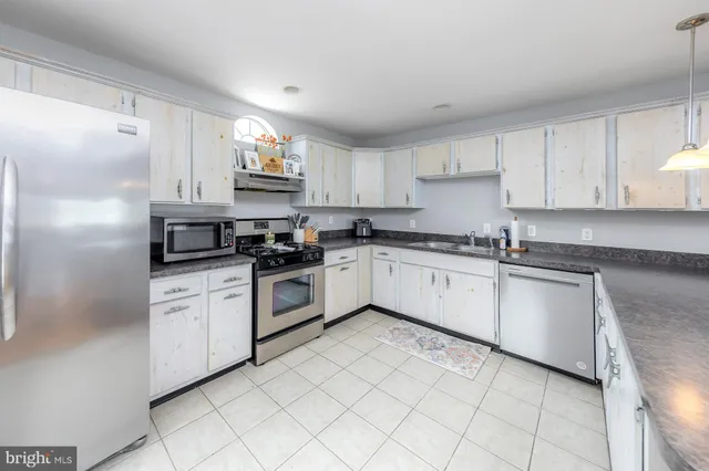 a white kitchen with granite top and stainless steel appliances