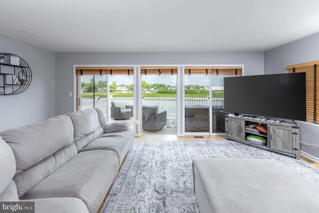 a living room with couch a flat screen tv and a large window