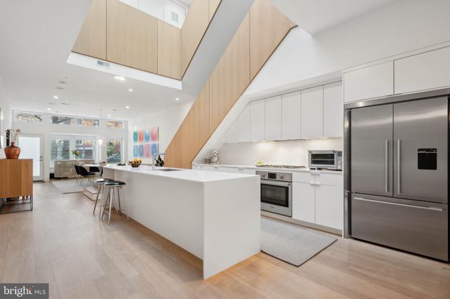 a kitchen with stainless steel appliances a refrigerator a stove a sink dishwasher and a dining table with wooden floor