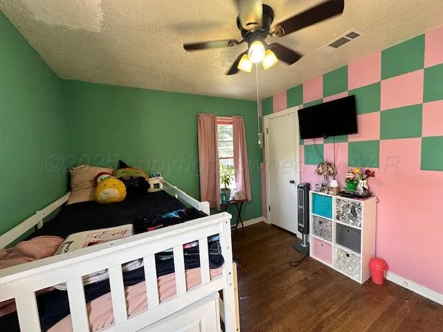 a bedroom with a bed and a flat tv screen on dresser