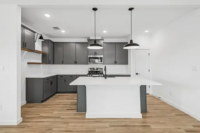 a kitchen with kitchen island a sink stainless steel appliances and wooden floor