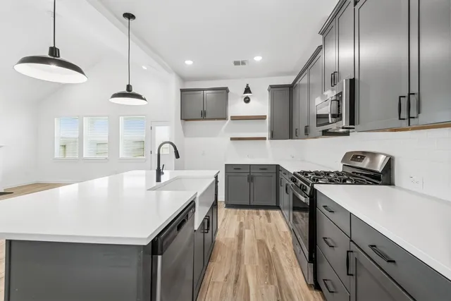 a kitchen with stainless steel appliances granite countertop a sink a stove and a wooden floors