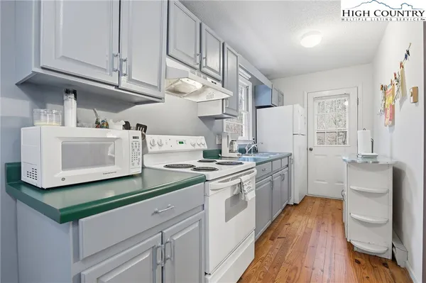 a kitchen with granite countertop white cabinets and white appliances