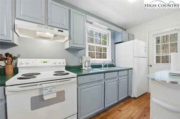 a kitchen with sink a stove and white cabinets