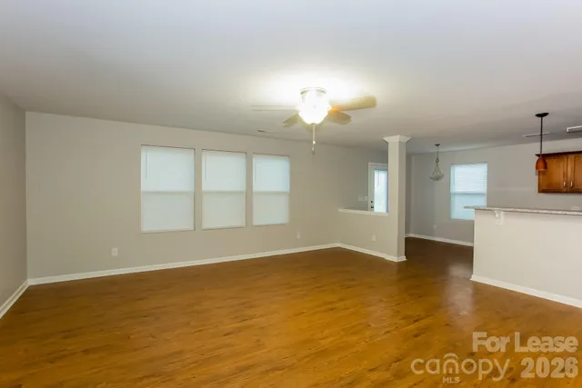 an empty room with wooden floor fireplace and windows