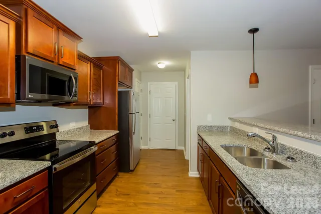 a kitchen with stainless steel appliances granite countertop a sink a stove and a refrigerator