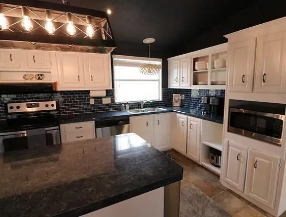 a kitchen with stainless steel appliances granite countertop a sink a stove and a microwave