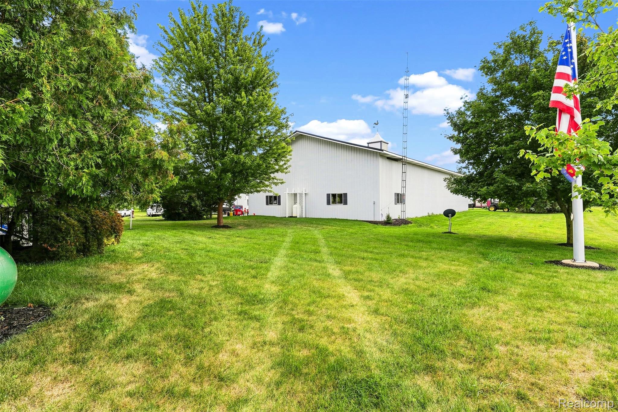 2971 Huron Line Road Cass City, MI 48726 - Photo 39 of 63 Expansive lawn area with mature trees and a white barn structure featuring multiple windows