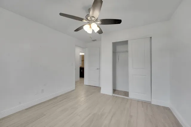 an empty room with wooden floor chandelier fan and closet area