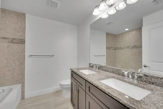 a bathroom with a granite countertop sink a toilet and a large mirror