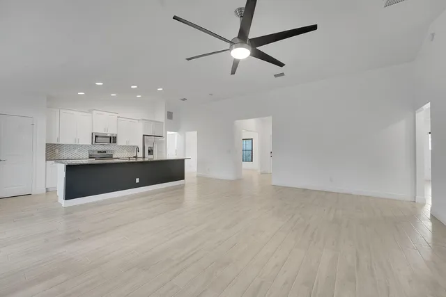 a large kitchen with stainless steel appliances a large counter top a sink a refrigerator and a window