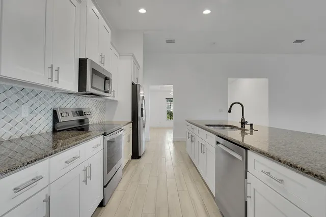a kitchen with stainless steel appliances granite countertop a sink stove and refrigerator