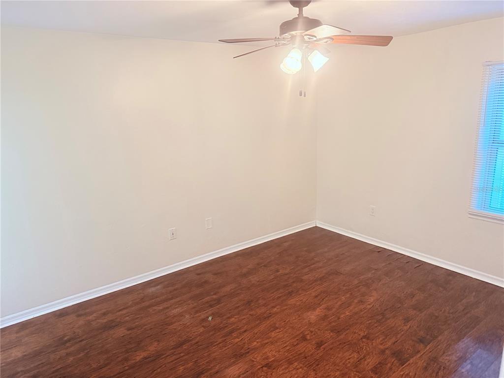 5134 Southwest 92nd Court Gainesville, FL 32608 - Photo 14 of 20 an empty room with wooden floor and fan