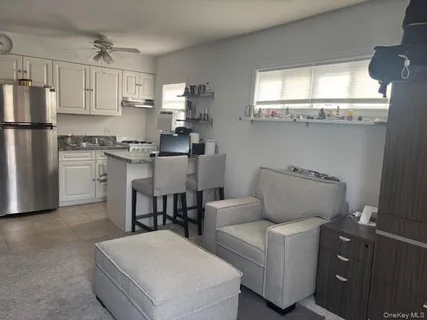 a living room with stainless steel appliances furniture a window and a refrigerator