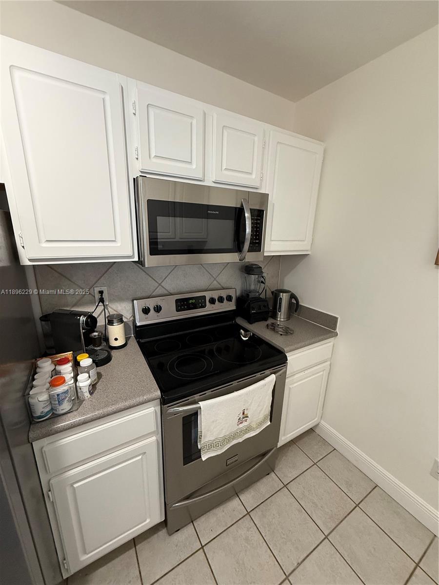 2665 Southwest 37th Avenue, Unit 1213 Miami, FL 33133 - Photo 11 of 54 a kitchen with granite countertop white cabinets and appliances