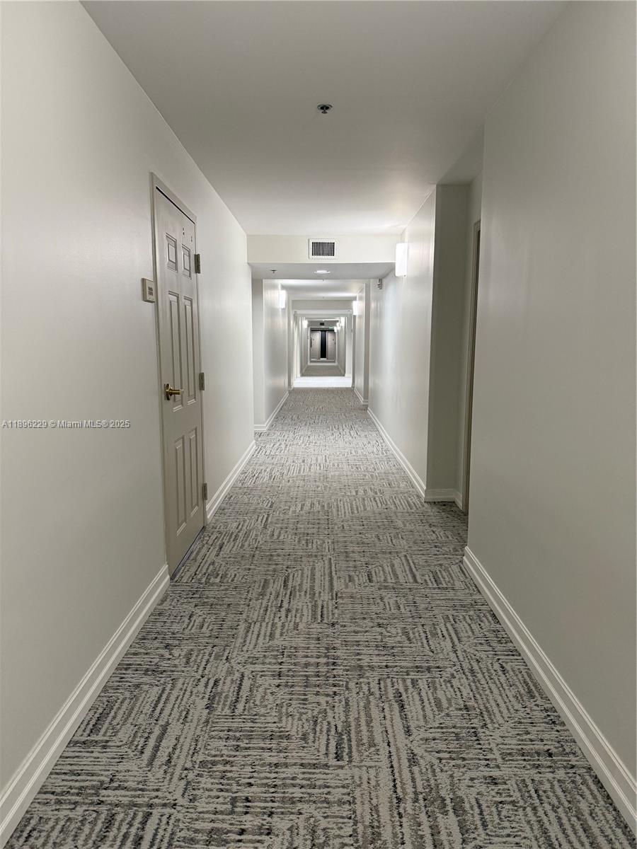 2665 Southwest 37th Avenue, Unit 1213 Miami, FL 33133 - Photo 6 of 54 a view of a hallway with wooden floor and a refrigerator
