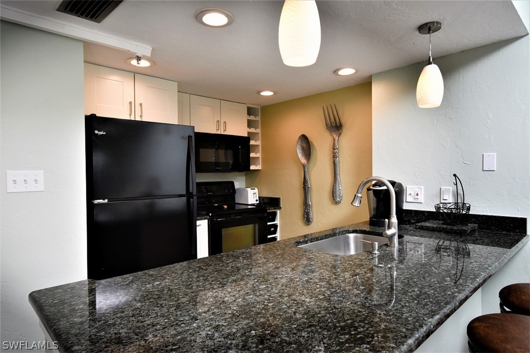 3170 Matecumbe Key Road, Unit 123 Punta Gorda, FL 33955 - Photo 4 of 25 a kitchen with stainless steel appliances granite countertop a sink refrigerator and microwave