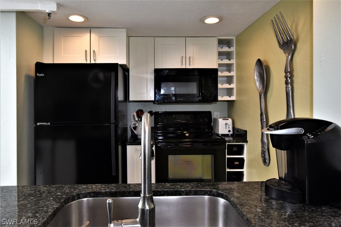 3170 Matecumbe Key Road, Unit 123 Punta Gorda, FL 33955 - Photo 6 of 25 a kitchen with stainless steel appliances granite countertop a refrigerator a stove a microwave oven and a sink with wooden floor