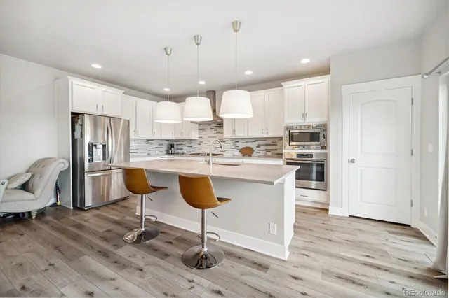 a kitchen with granite countertop a stove a sink a dining table and chairs with wooden floor