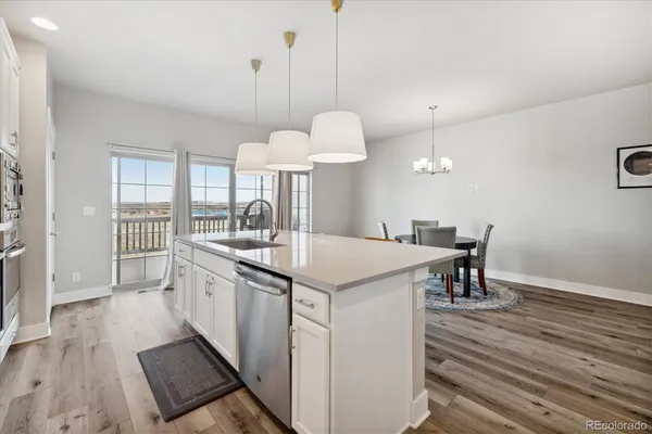 a kitchen with a table chairs a sink dishwasher a stove and a refrigerator with wooden floor