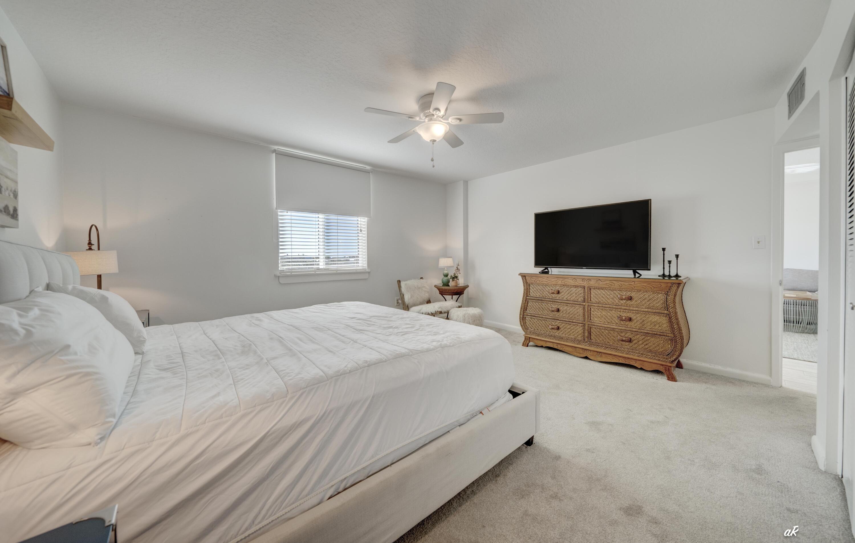 30 Moreno Point Road, Unit 404A Destin, FL 32541 - Photo 20 of 52 a spacious bedroom with a bed and a flat screen tv