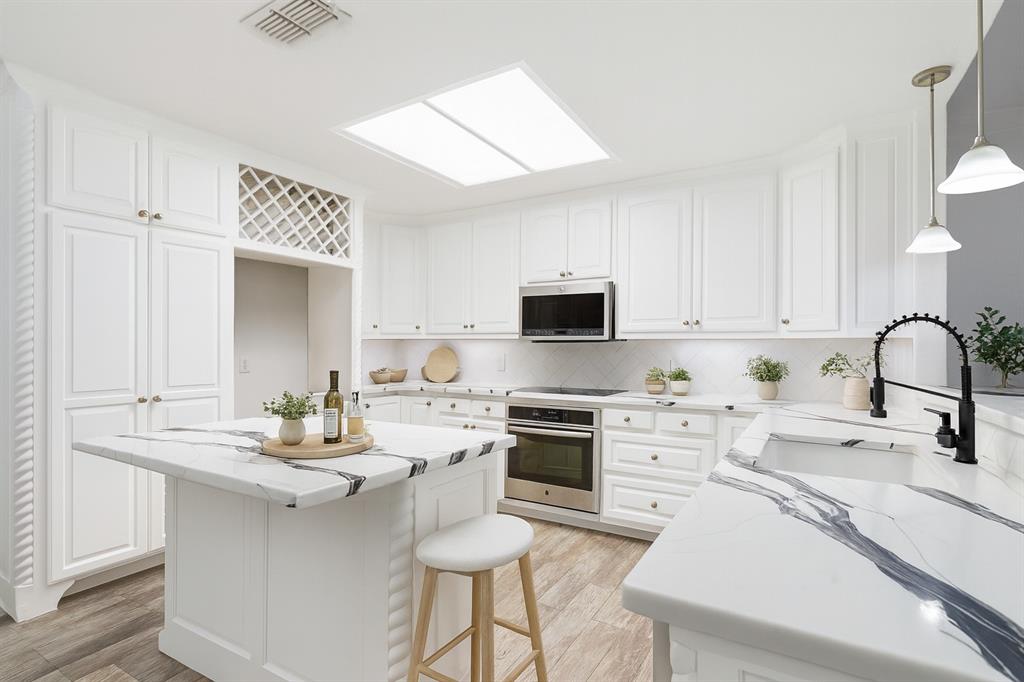 a kitchen with a sink white cabinets and stainless steel appliances