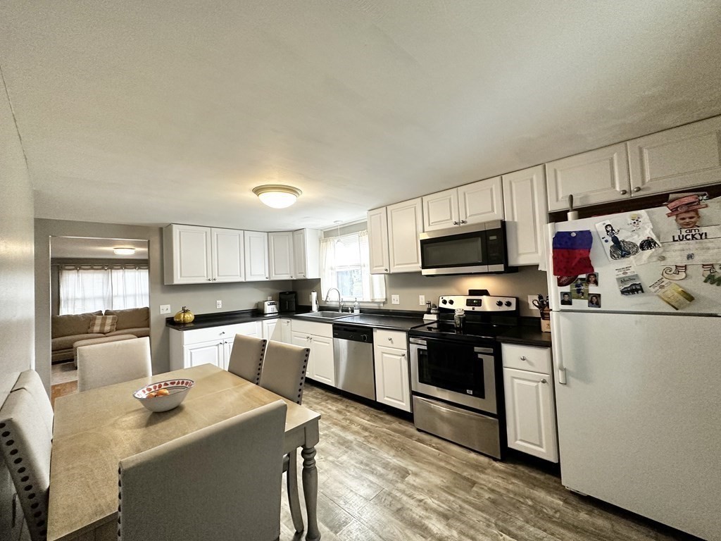 174 Chudy Street Three Rivers, MA 01080 - Photo 13 of 31 a kitchen with stainless steel appliances a stove top oven a sink a refrigerator white cabinets and wooden floor