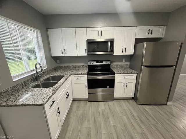 a kitchen with a sink a refrigerator a microwave and cabinets