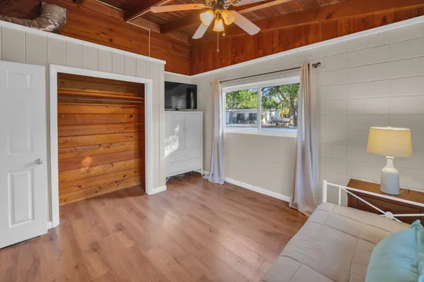 a view of a livingroom with wooden floor a ceiling fan and window