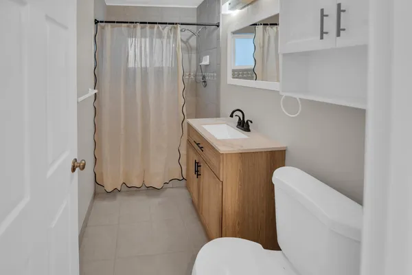 a bathroom with a sink a toilet and shower curtain