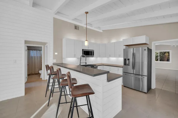 a kitchen with kitchen island a refrigerator and a stove top oven