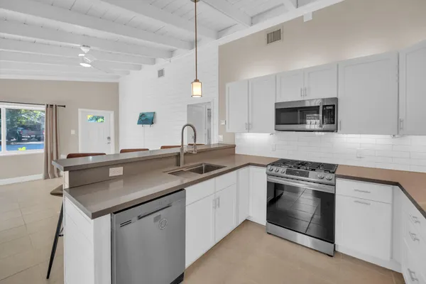 a kitchen with stainless steel appliances granite countertop a sink stove oven and white cabinets