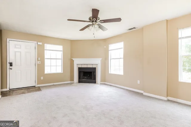 a view of an empty room with chandelier fan and fire place
