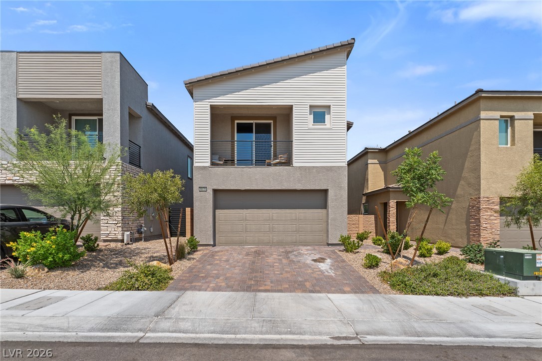 8879 Roadrunner Ravine Street Las Vegas, NV 89166 - Photo 1 of 39 A contemporary façade features a recessed balcony and an integrated garage, complemented by desert-friendly landscaping.