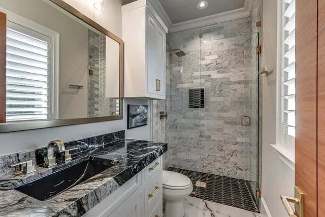 a bathroom with a granite countertop sink a toilet a mirror and shower