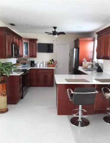 a room with kitchen island stainless steel appliances a sink stove and refrigerator