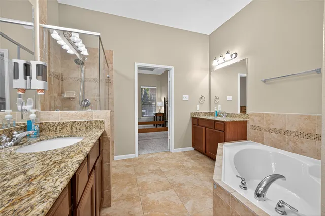 a bathroom with a granite countertop tub a sink and a mirror