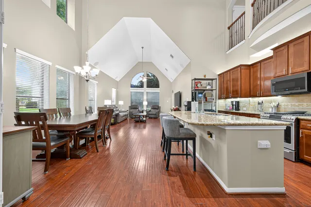 a kitchen with stainless steel appliances granite countertop a table chairs stove a sink dishwasher and cabinets with wooden floor