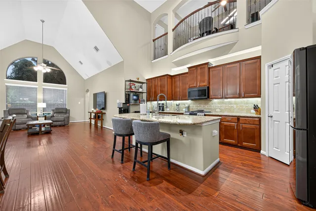 a kitchen with stainless steel appliances granite countertop wooden floors a stove and a refrigerator